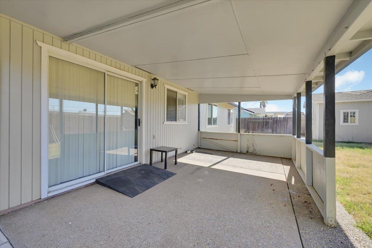 Covered concrete patio with a sliding glass door and small table.