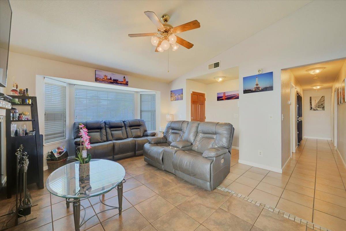 Living room with gray leather recliners, a glass coffee table, tiled floor, and ceiling fan.