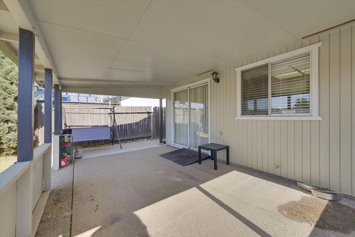 Covered backyard patio with blue posts, a porch swing, and sliding glass door.