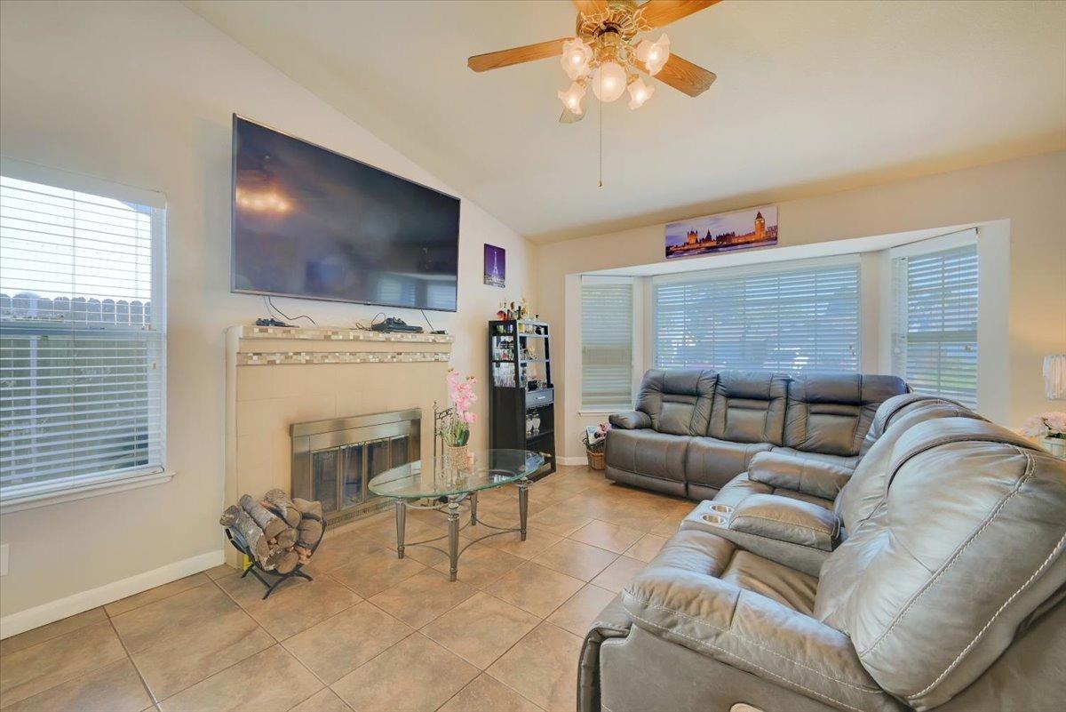 Living room with a gray leather sectional, tiled floor, fireplace, and wall-mounted television.