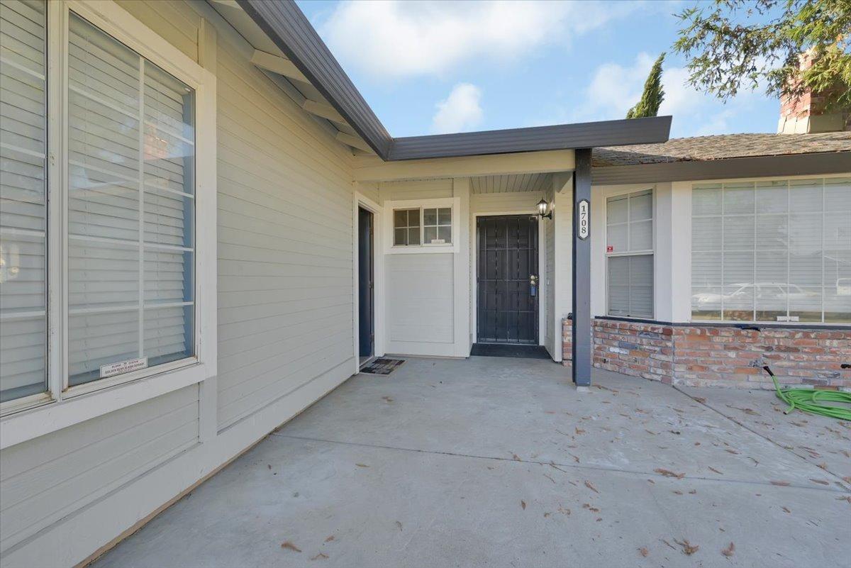 Home entrance with a covered concrete porch, dark front door, and brick planter.