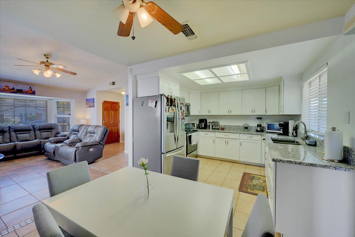 Open-plan kitchen and living room with white cabinets, granite counters, and a gray sectional sofa.