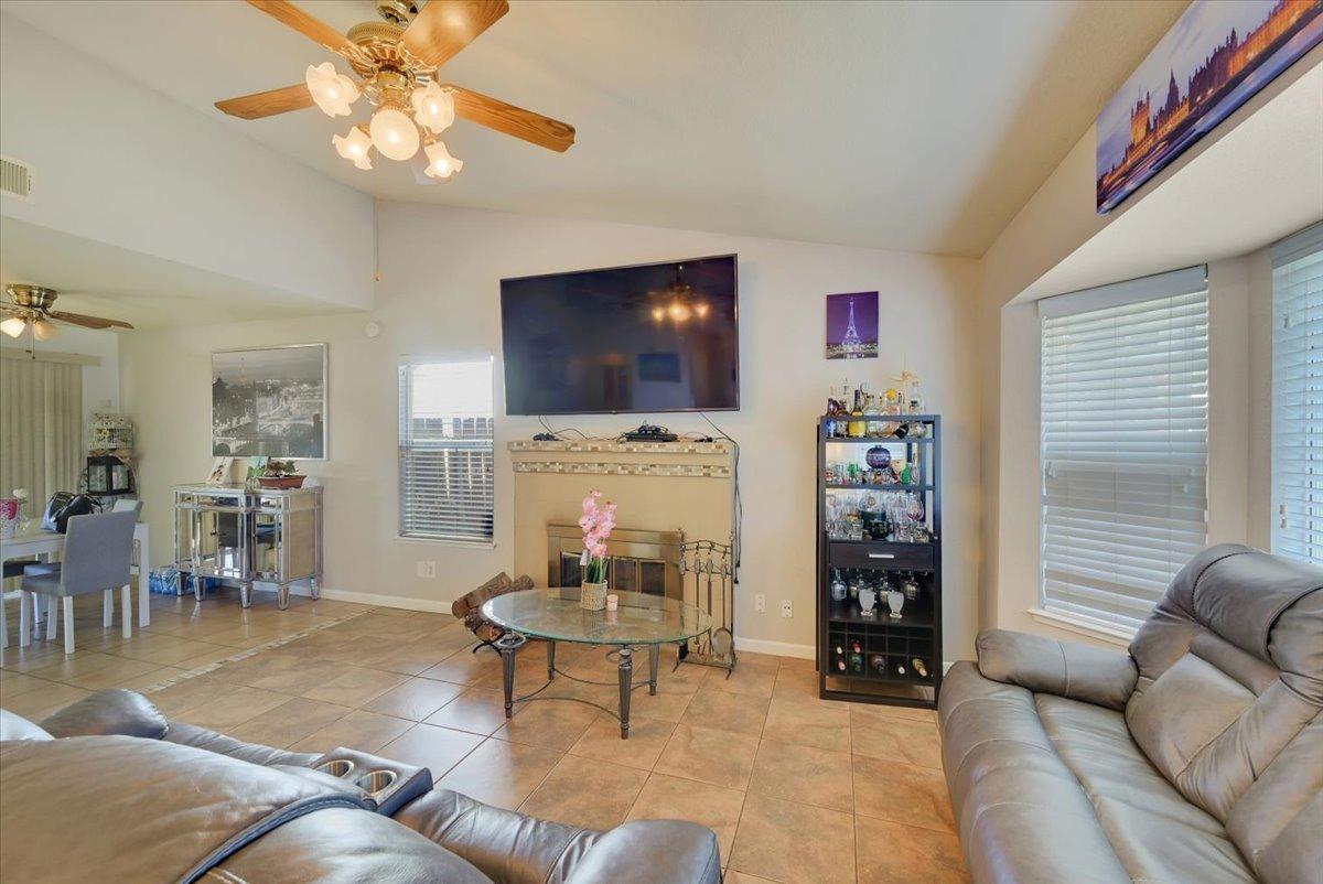 Living room with leather sofas, tiled floors, and a fireplace beneath a large television.