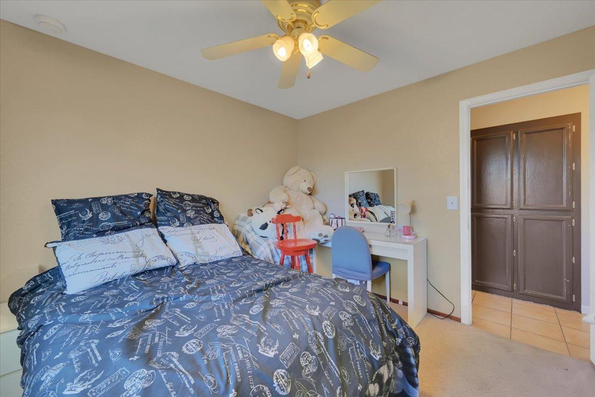 Bedroom with navy patterned bedding, a desk and chair, stuffed animals, and dark wood closet doors.