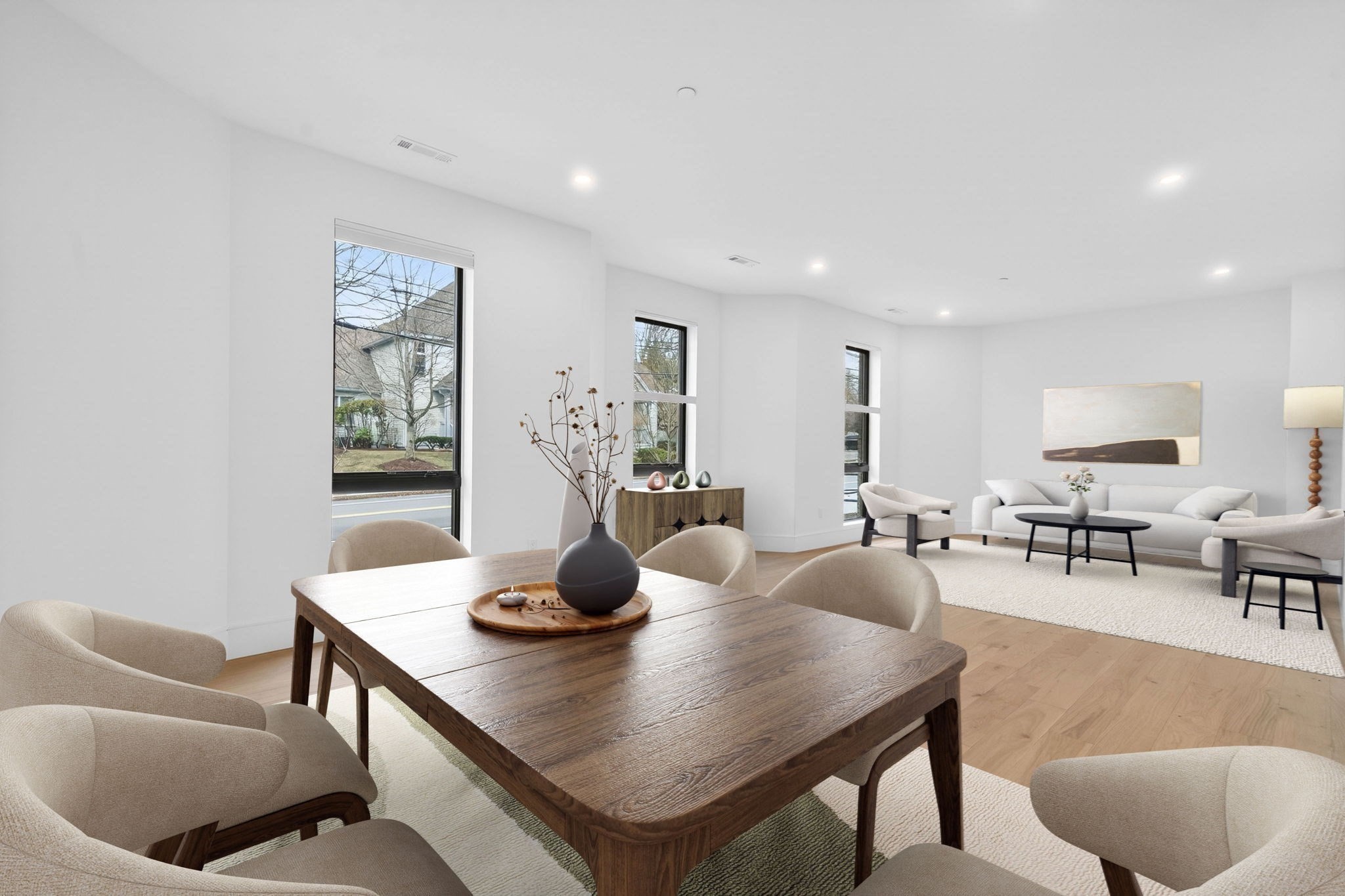 Open-plan living and dining room with a large wooden table and a bright seating area.
