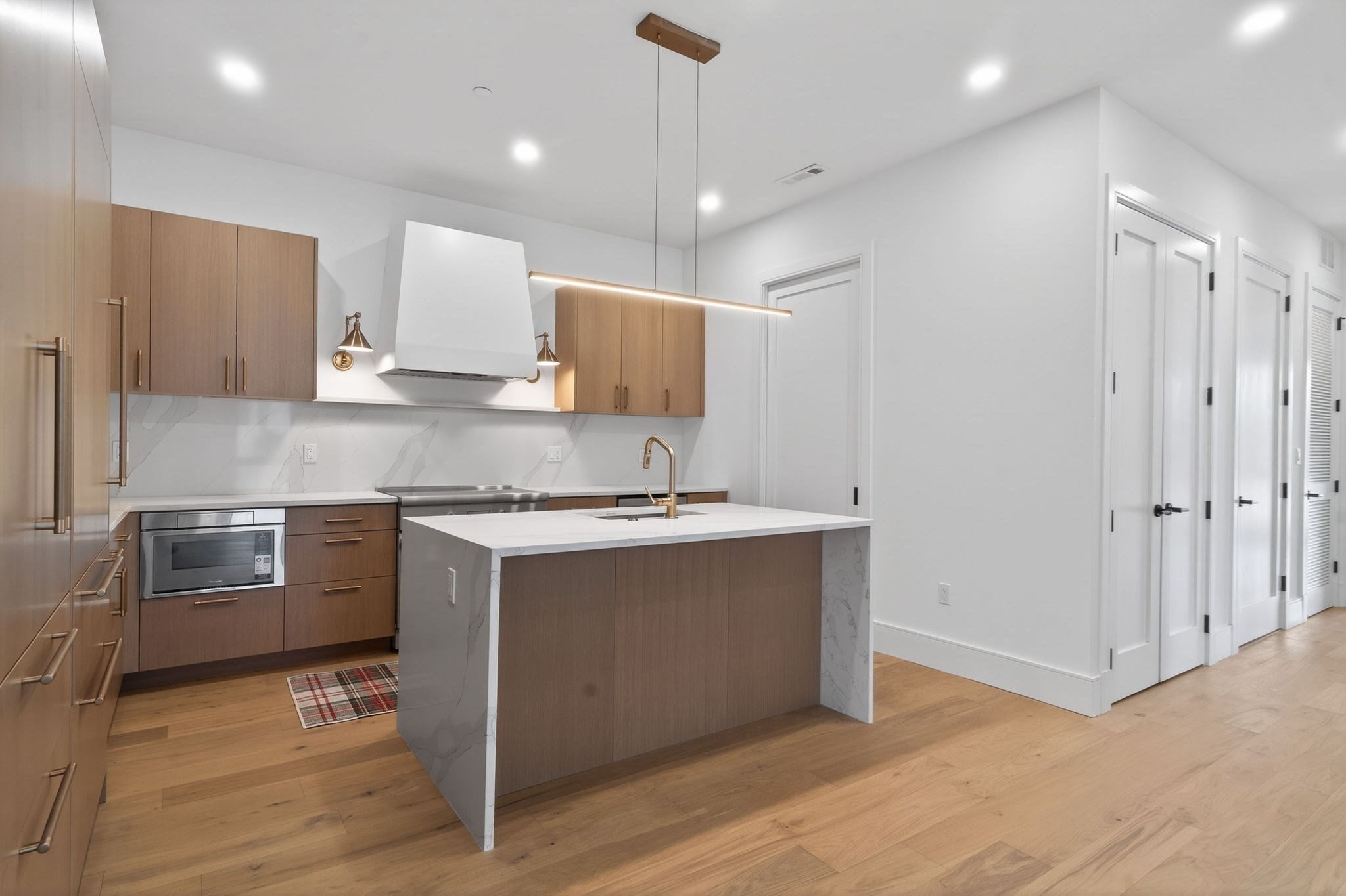 Modern kitchen with wood cabinetry, a waterfall-edge island, and brass fixtures.