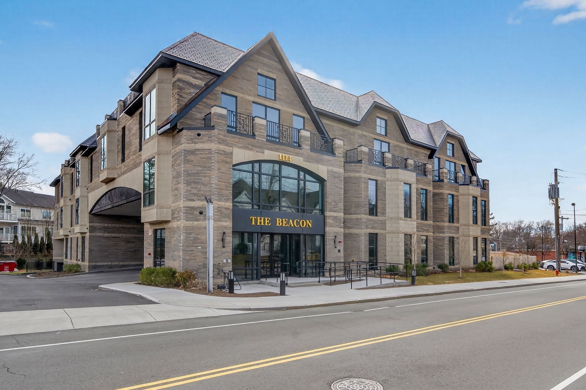 The Beacon condominium building with stone-and-brick facade, gabled roofs, and arched glass entrance.