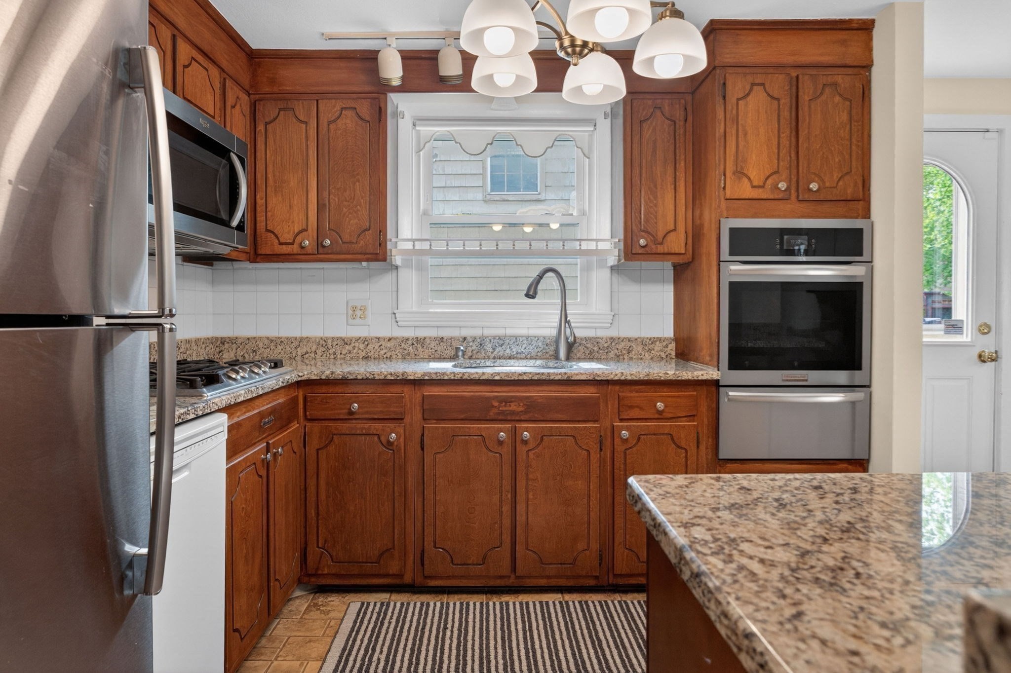 Kitchen with wood cabinets, granite counters, stainless appliances, and a sink beneath the window.