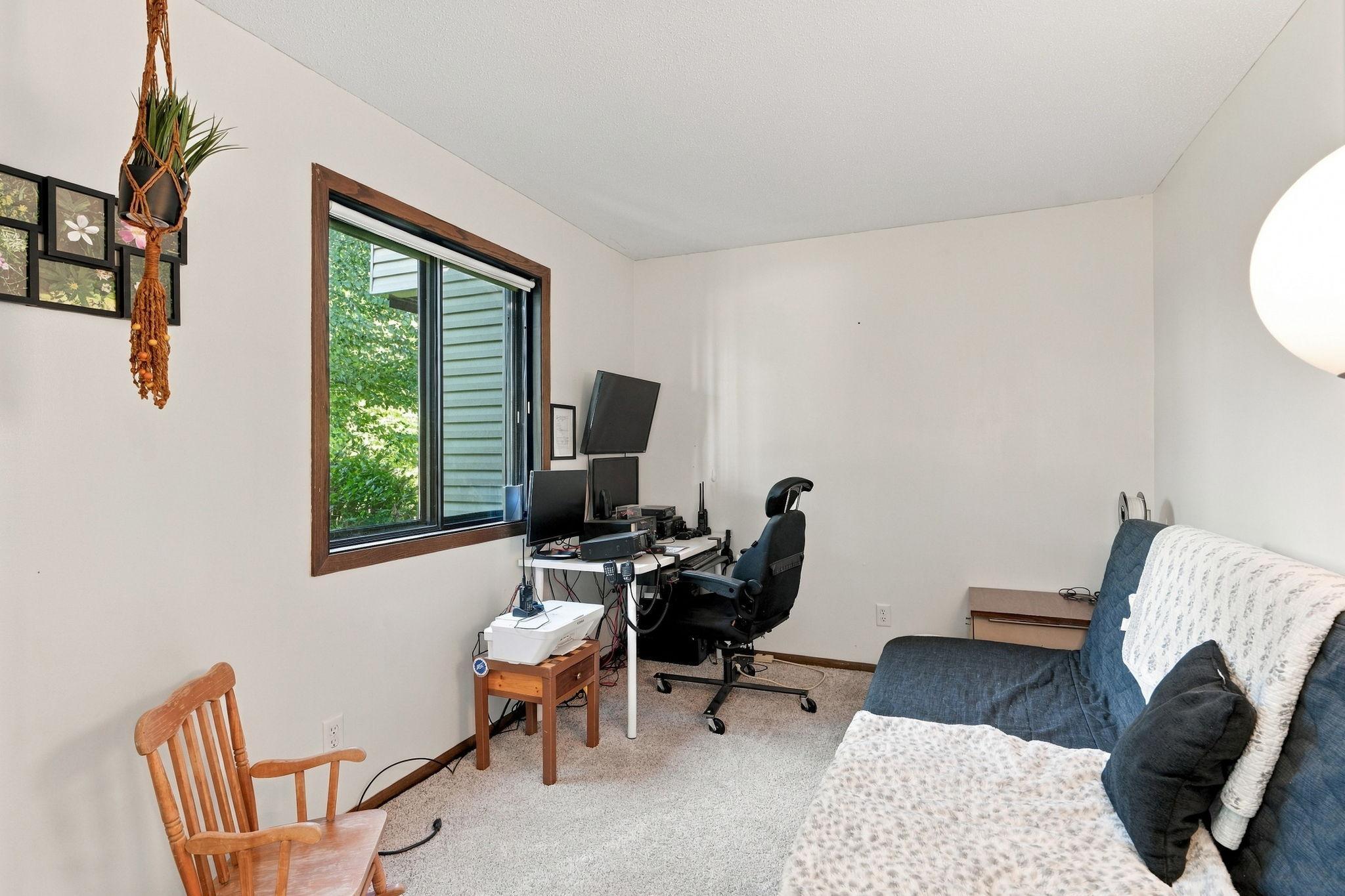 Home office with a computer workstation by the window and a blue sofa.