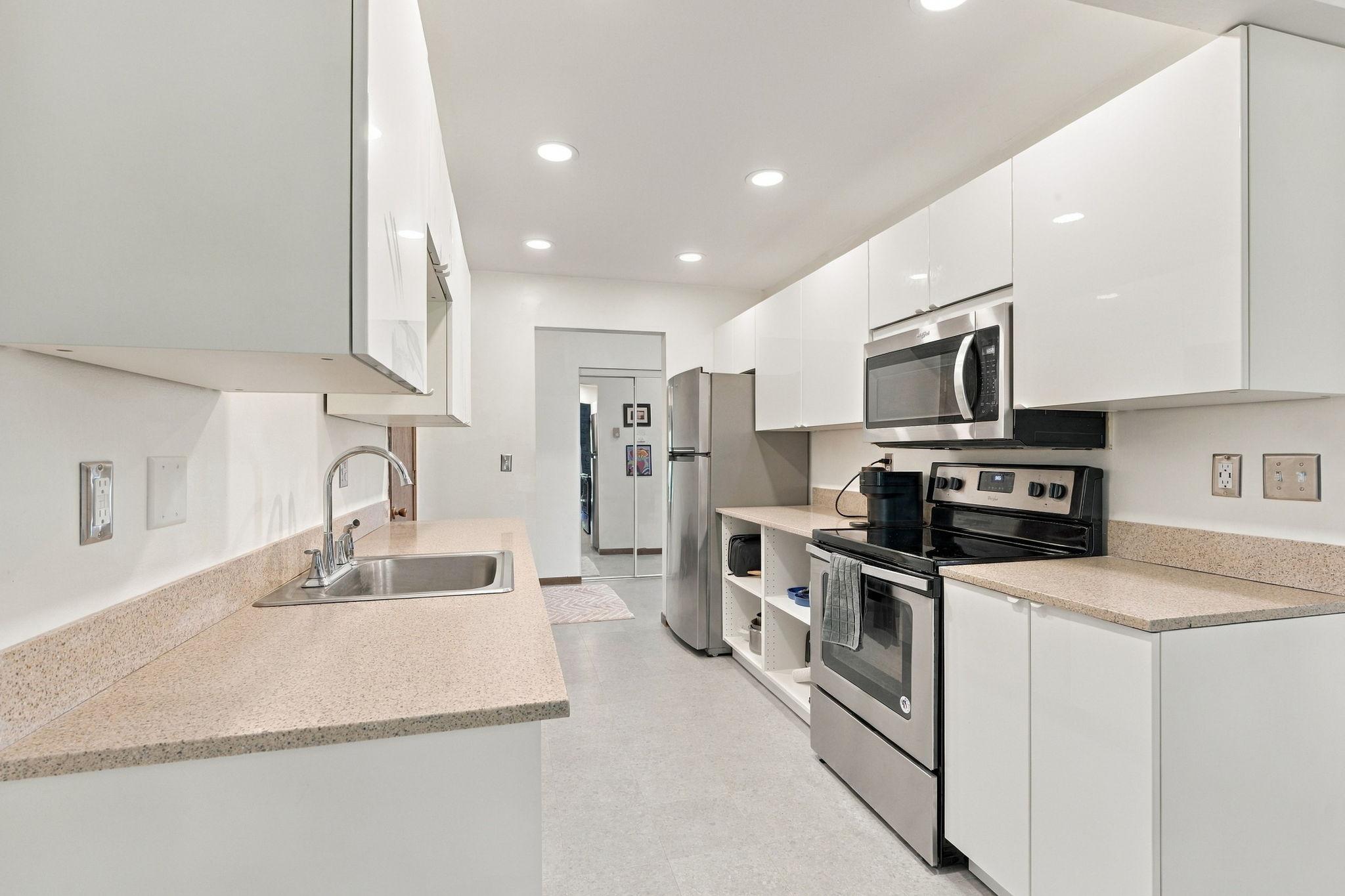 Kitchen with white cabinets, speckled counters, and stainless-steel appliances.