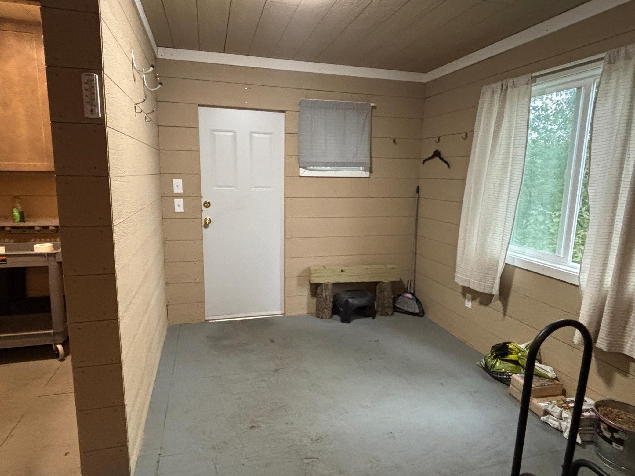 Entryway with a white door, curtained window, wall hooks, and a small bench.
