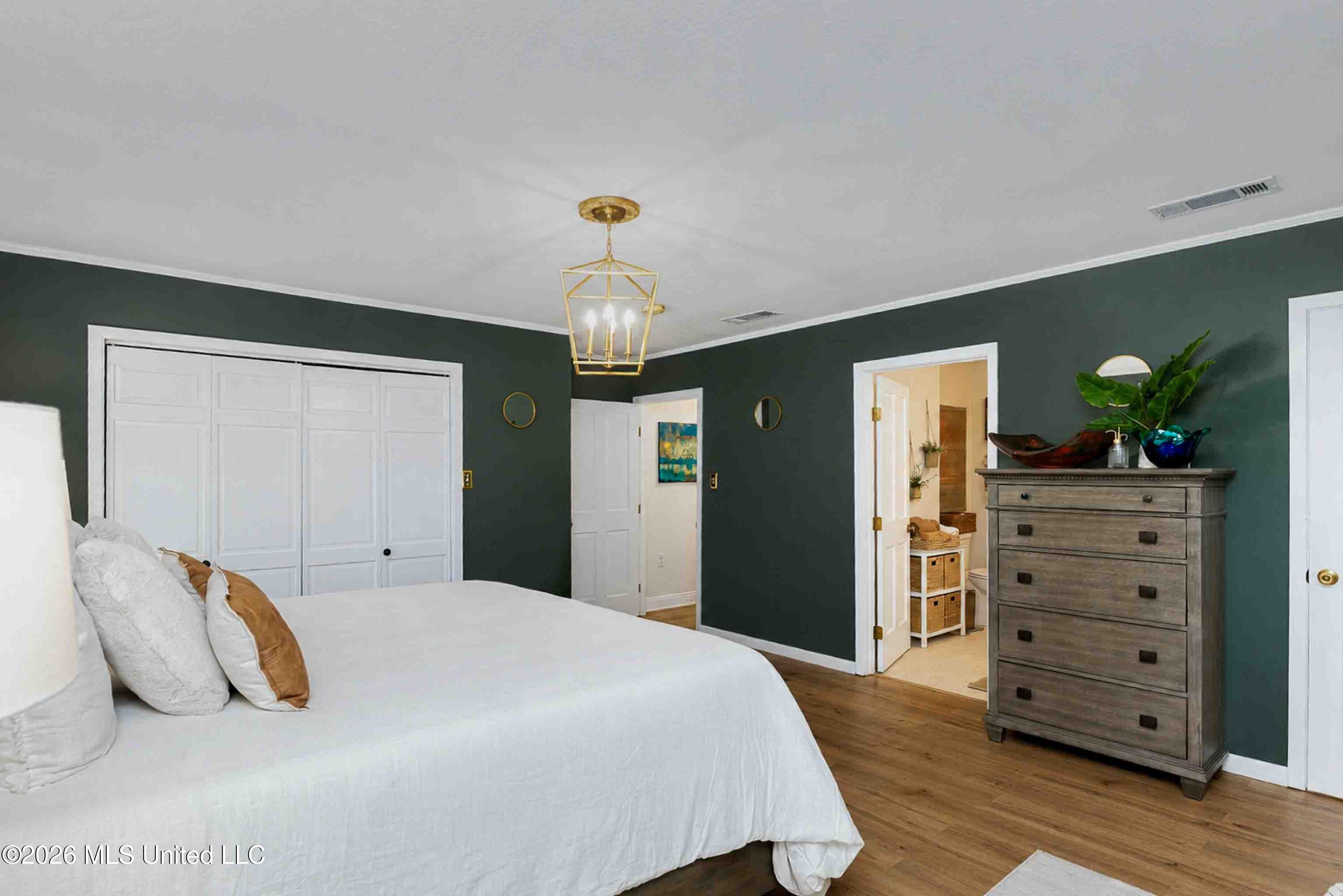 Bedroom with dark green walls, a white bed, paneled closet doors, and a gray chest of drawers.