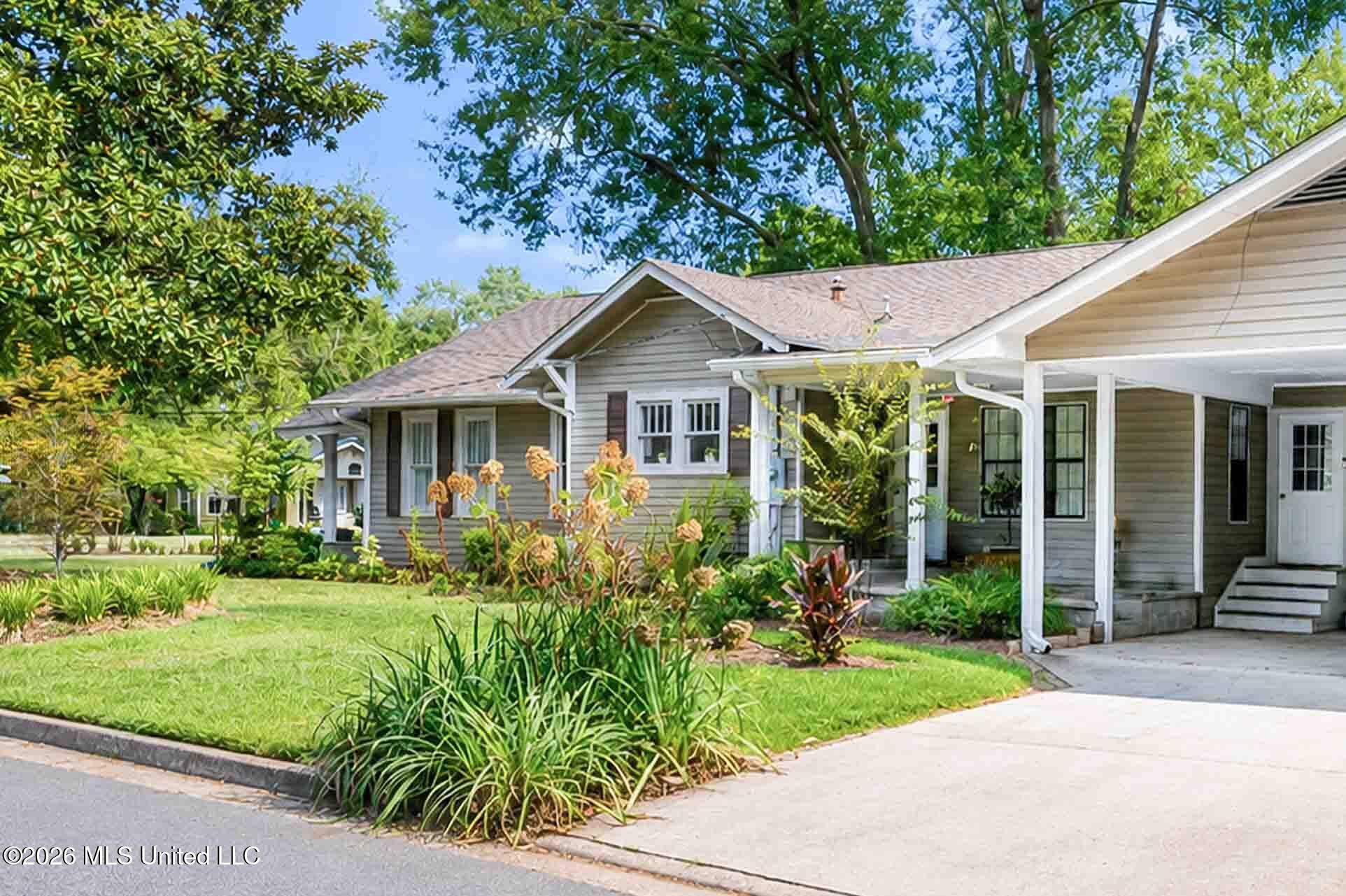 Gray single-story home with a white-columned porch, landscaped yard, and wide driveway.