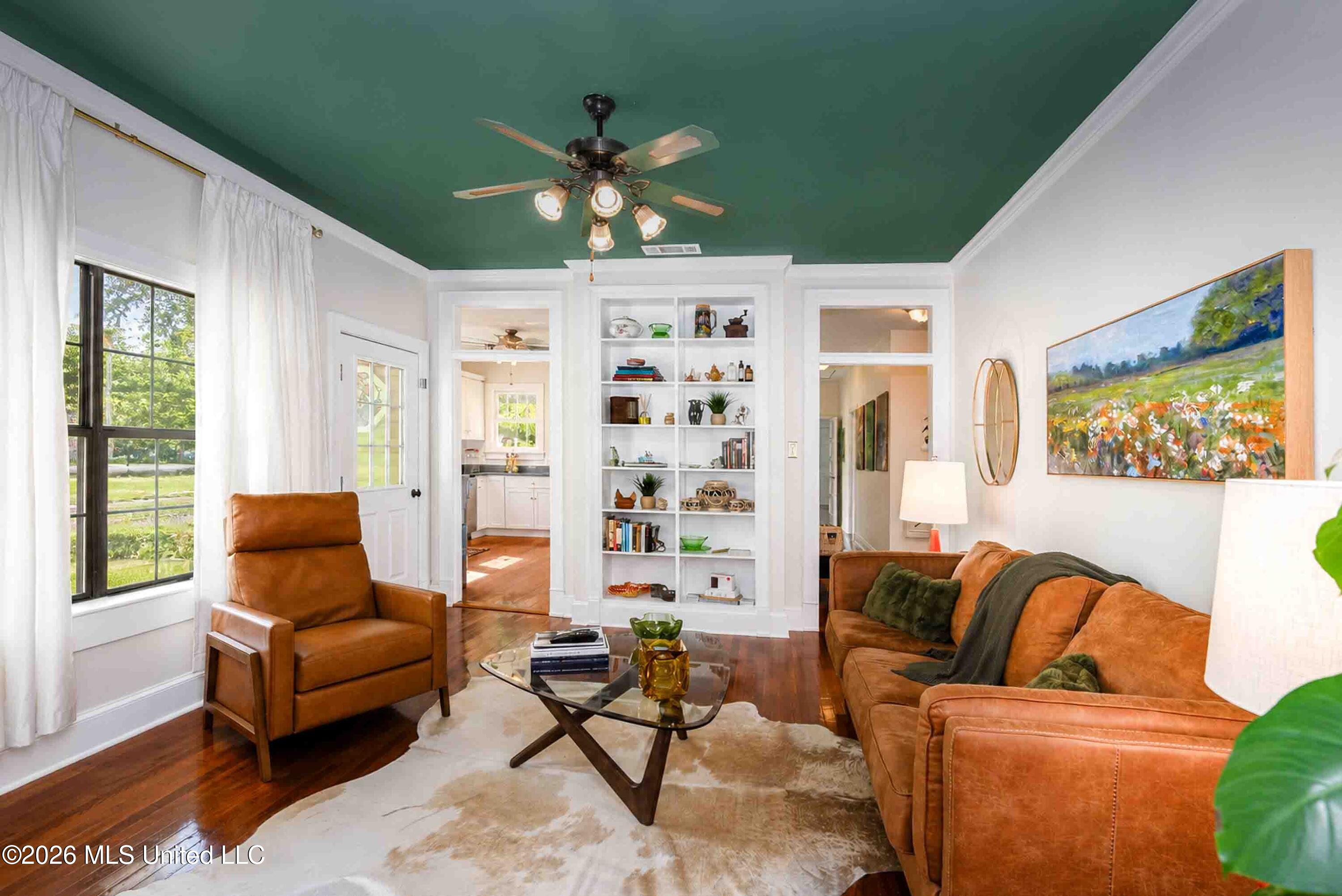 Living room with a green ceiling, built-in bookshelves, and tan leather seating.