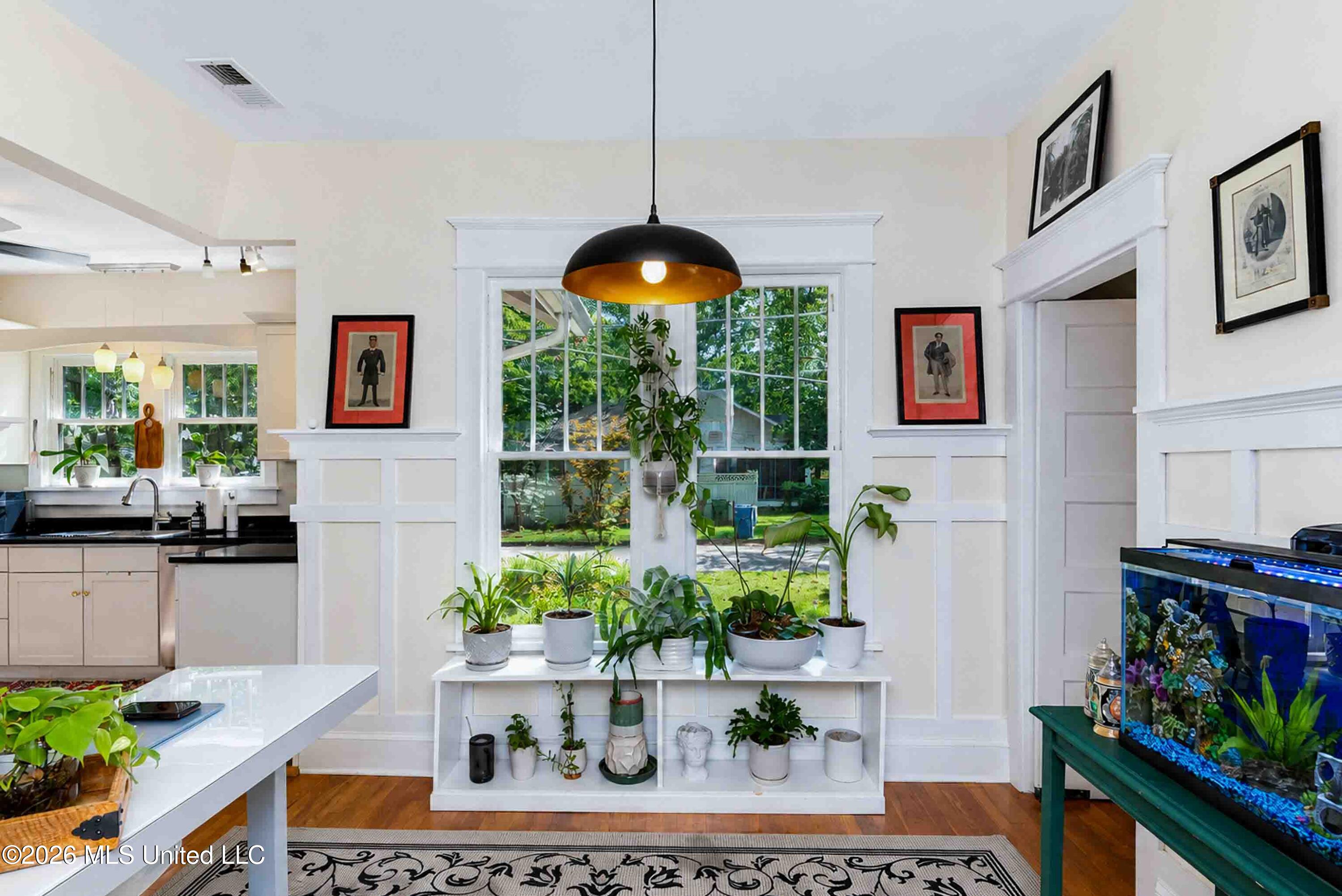 Bright interior with a garden-facing window lined with potted plants and a colorful aquarium.