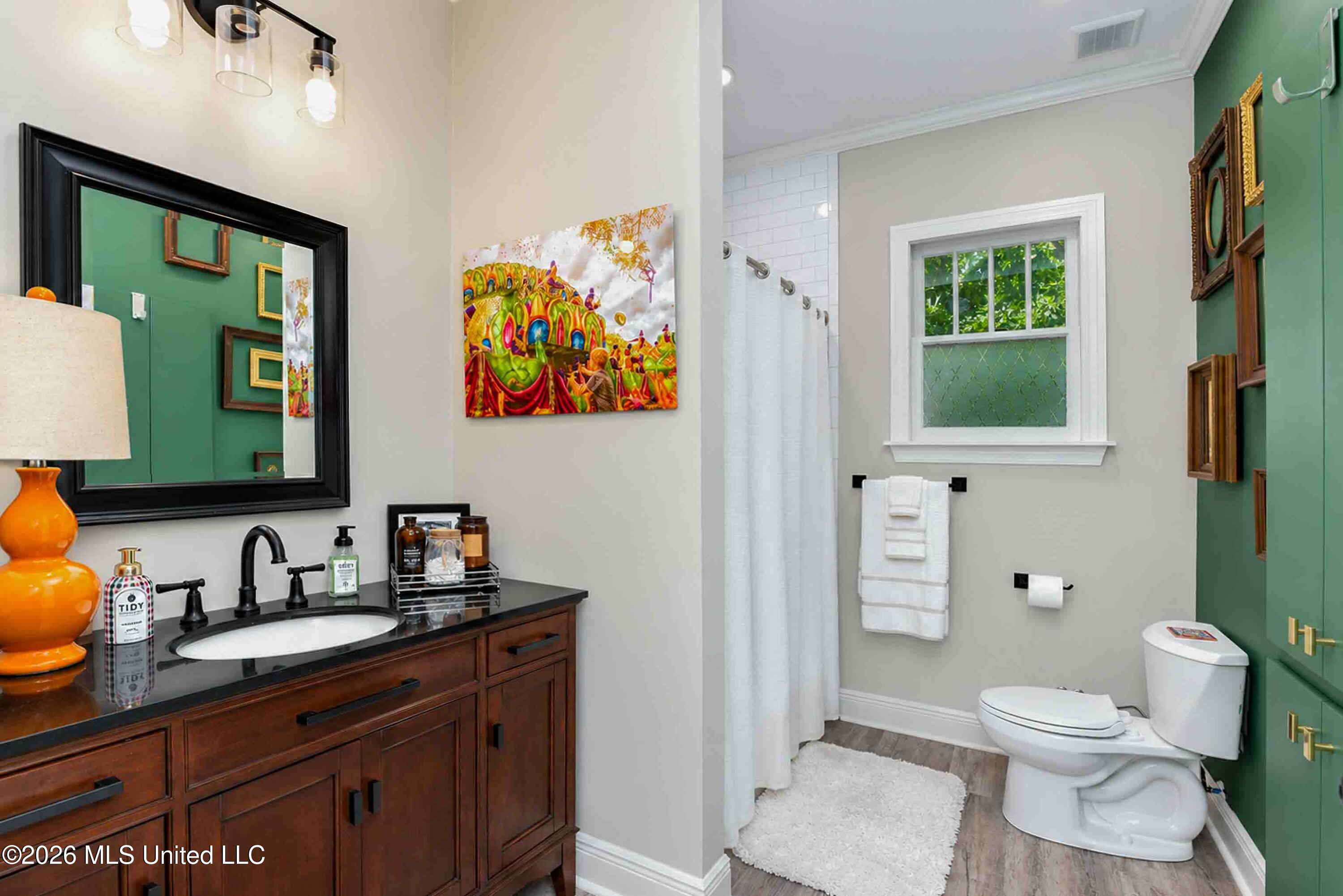 Bathroom with a dark wood vanity, black countertop, white shower curtain, and green cabinetry.