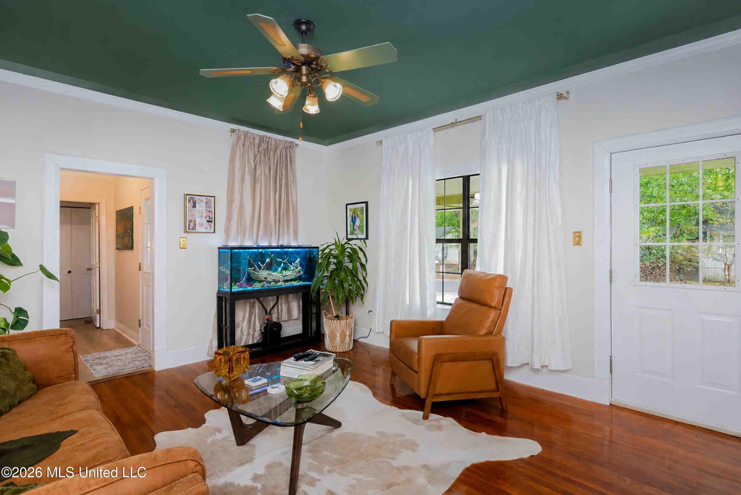 Living room with a dark green ceiling, aquarium, tan leather seating, and hardwood floors.