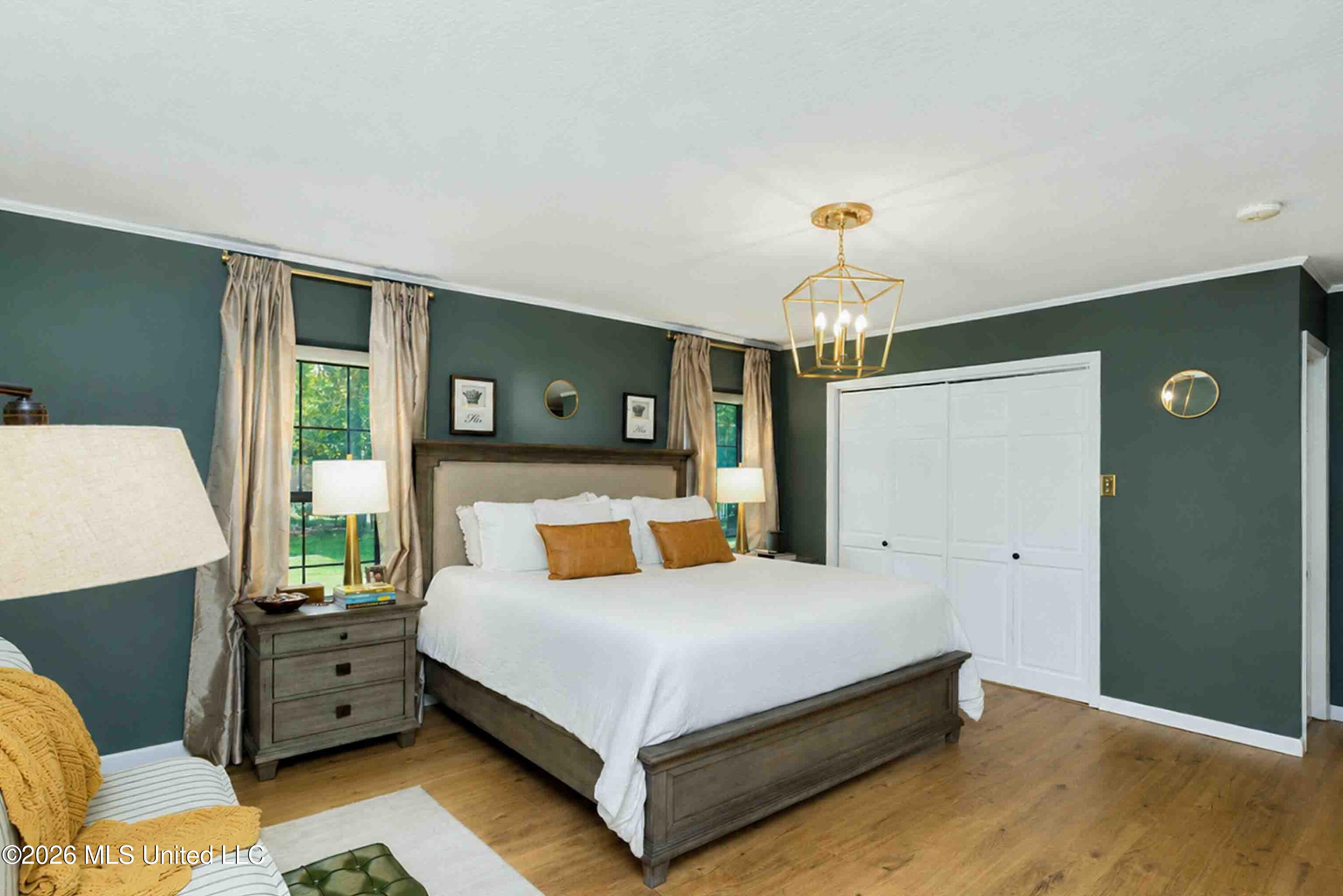 Bedroom with a large white-covered bed, dark green walls, and curtained windows.
