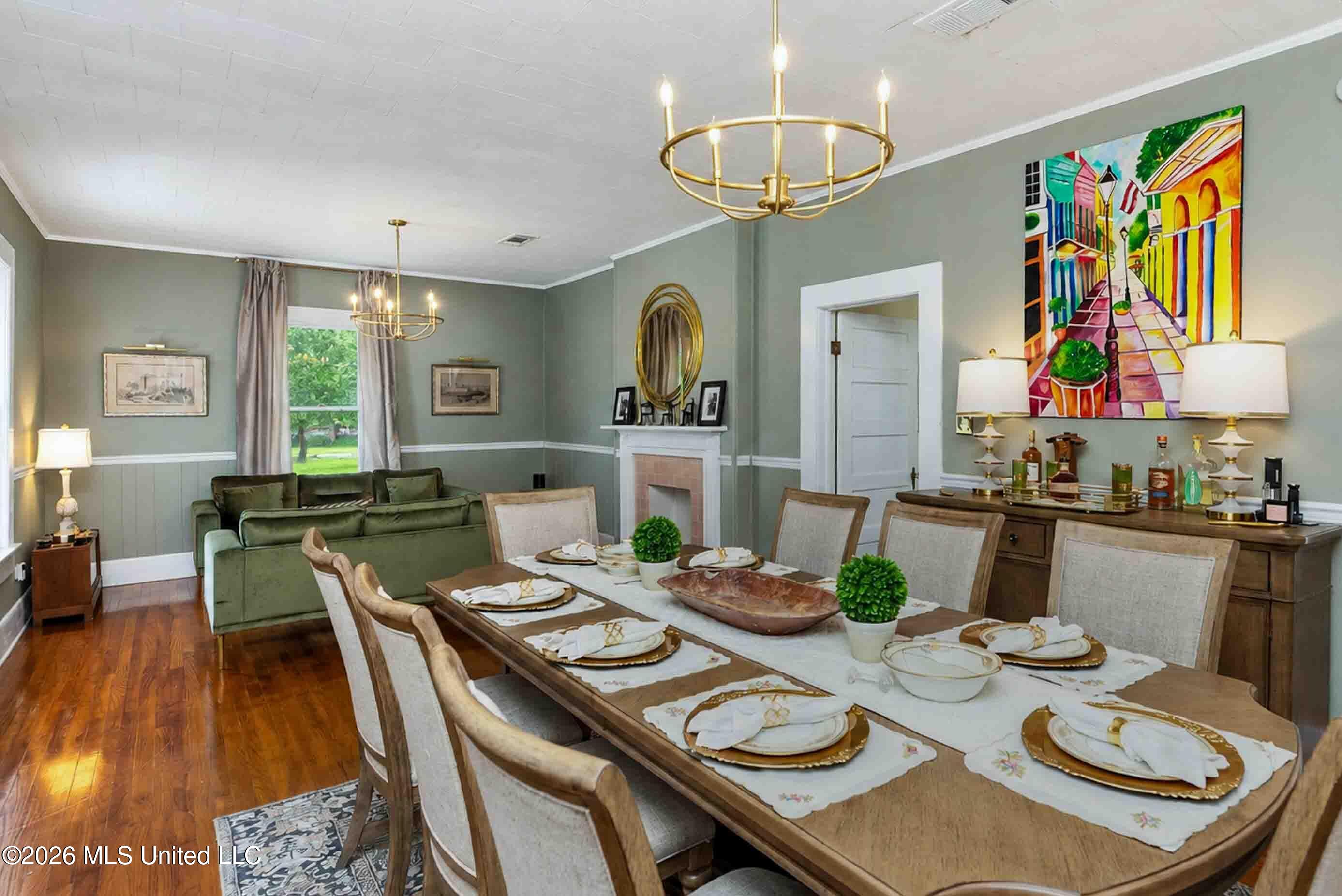 Dining room with a set table beside a green sofa and fireplace.