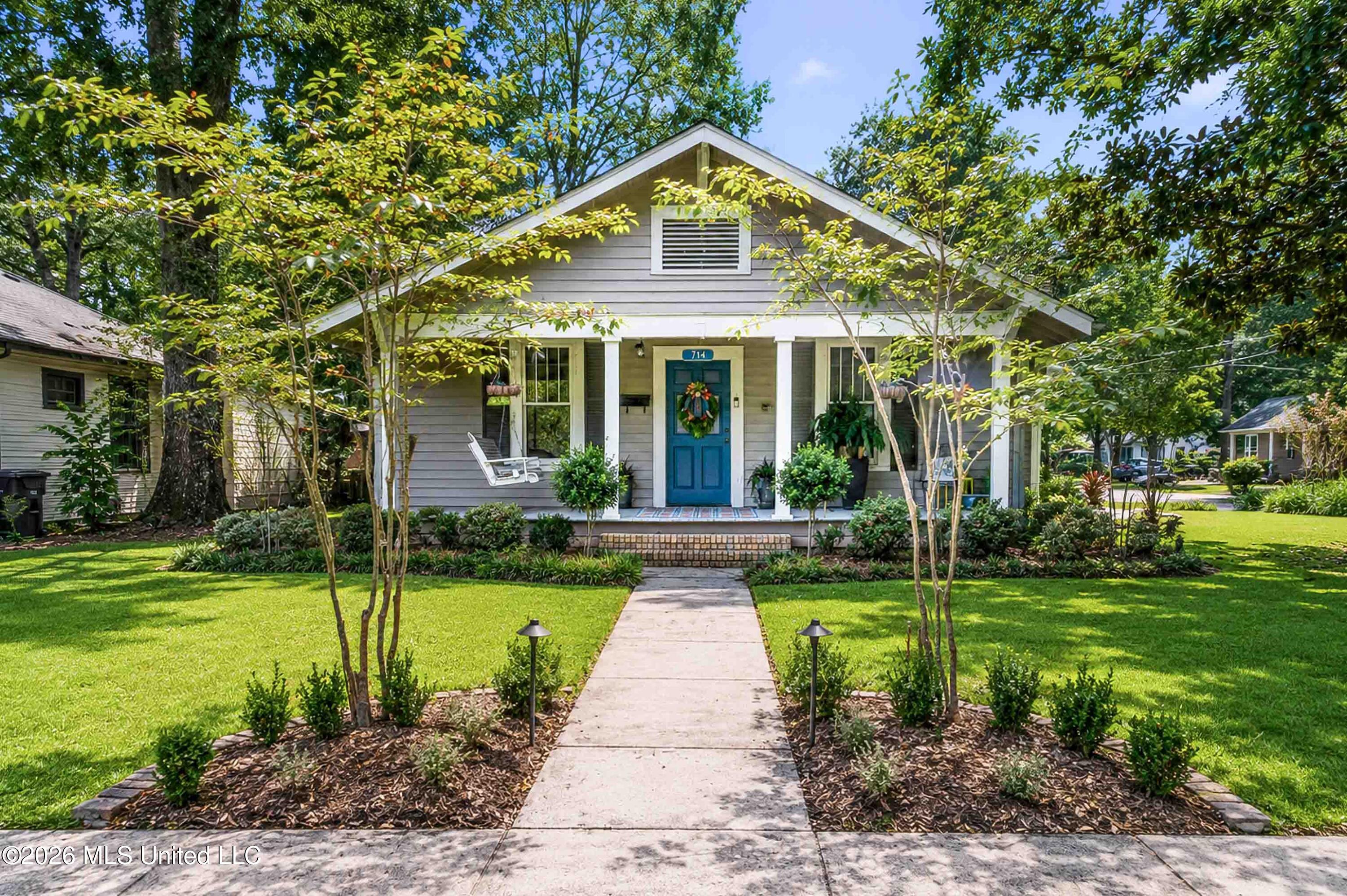 Gray home with a blue front door, covered porch, and landscaped front yard.