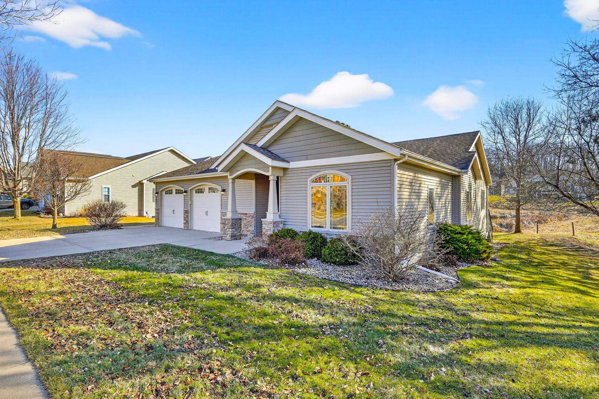 Gray-sided home with a two-car garage, front gables, and landscaped lawn.