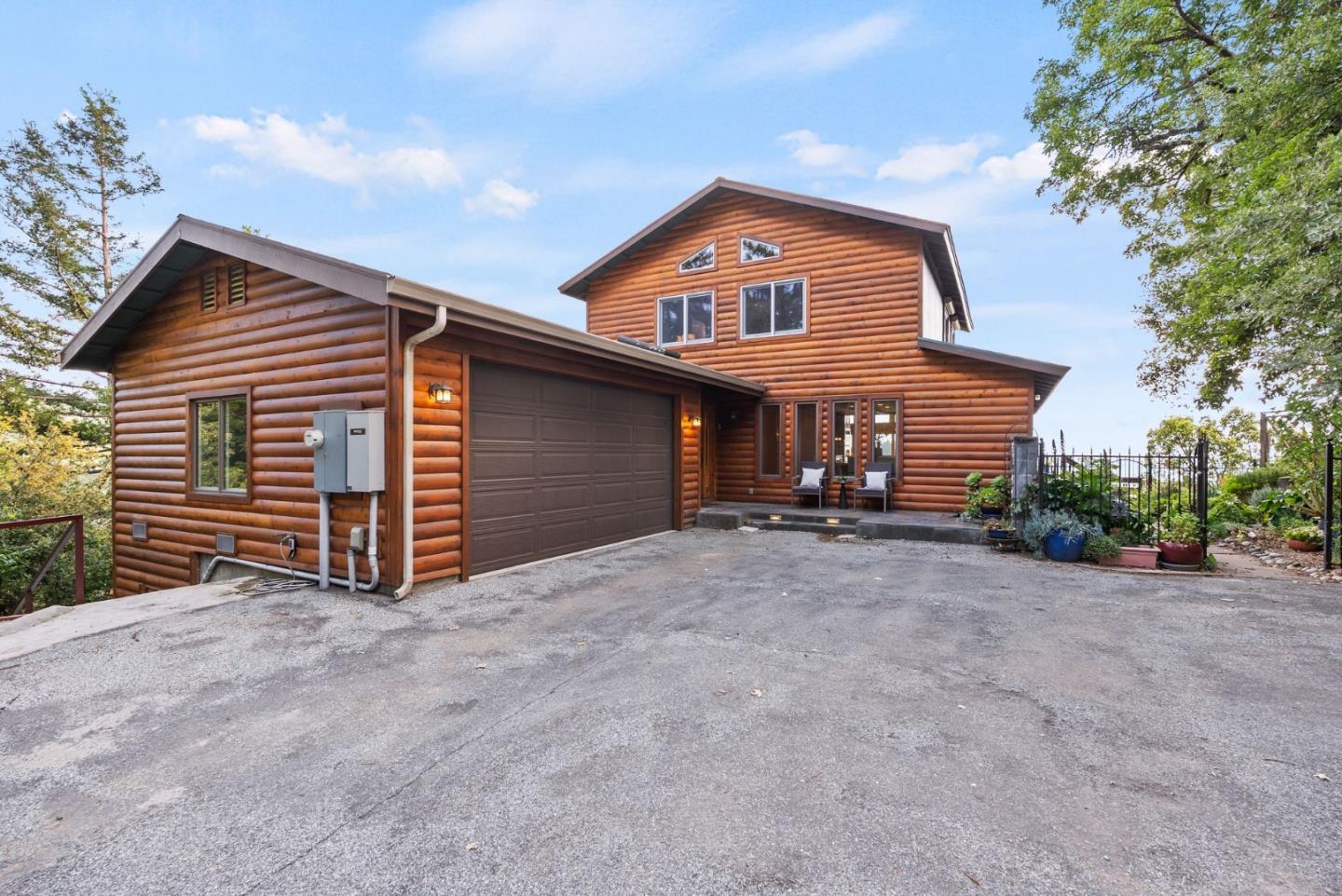 Log-sided home with an attached garage and broad paved driveway.