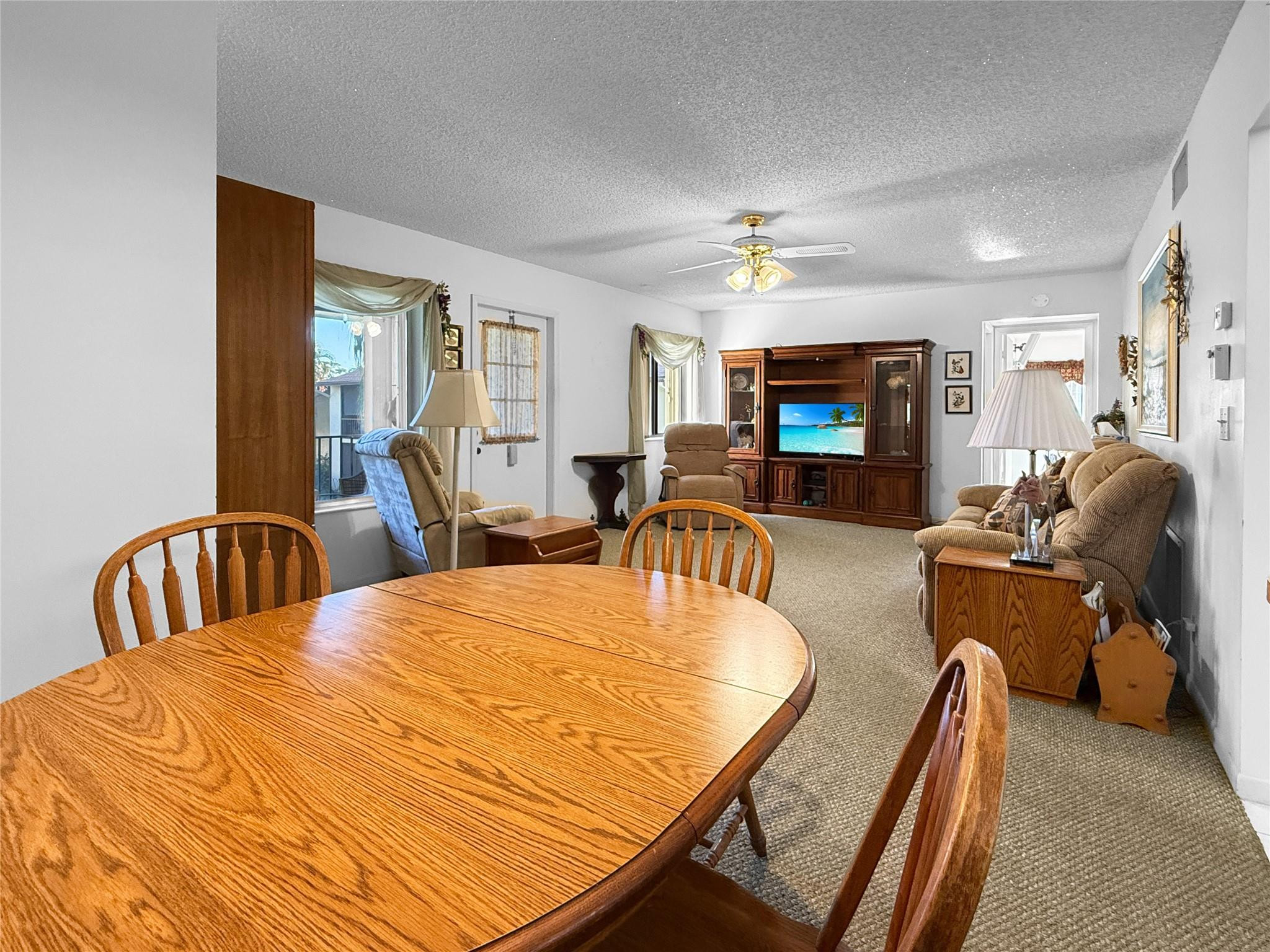 Furnished living and dining area with a large wooden table and dark wood entertainment center.