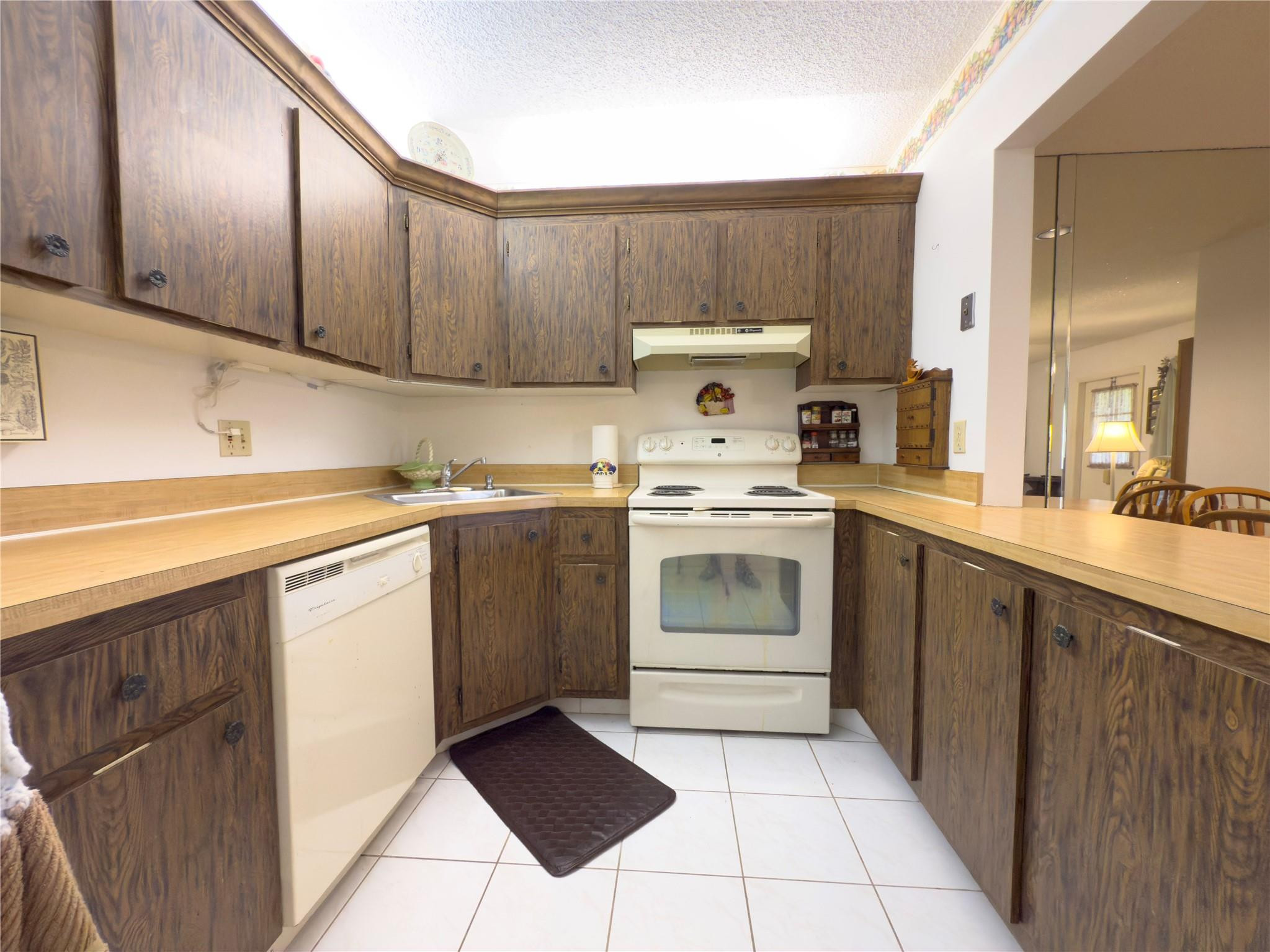 Kitchen with dark wood cabinets, light countertops, and white appliances.