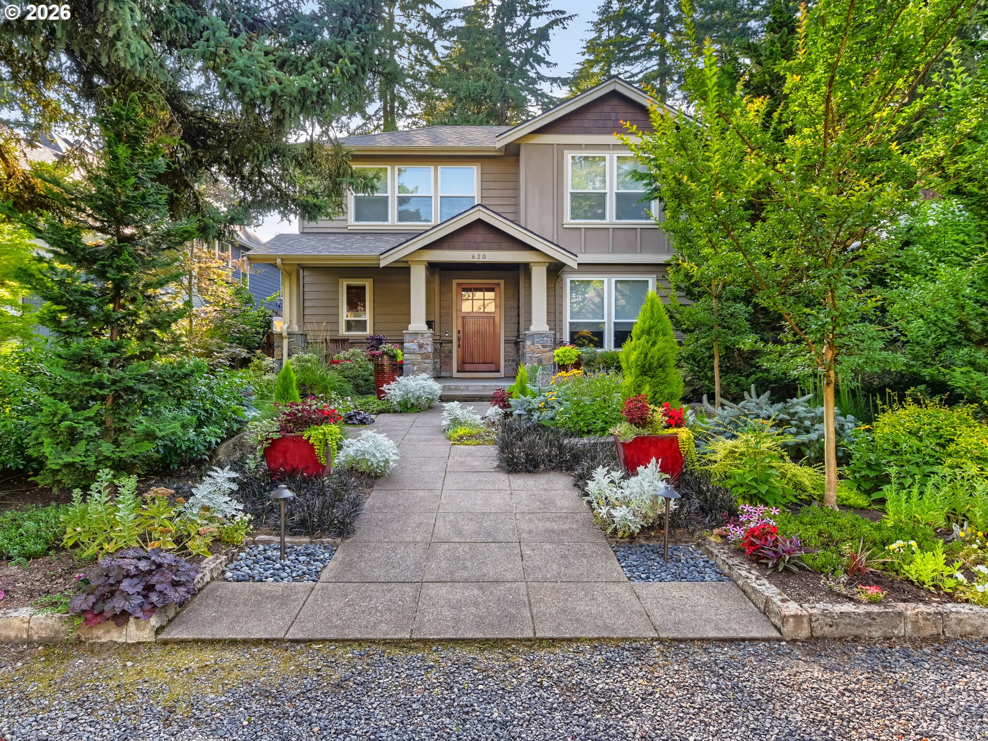 Two-story house with a covered entry and a flower-lined walkway.