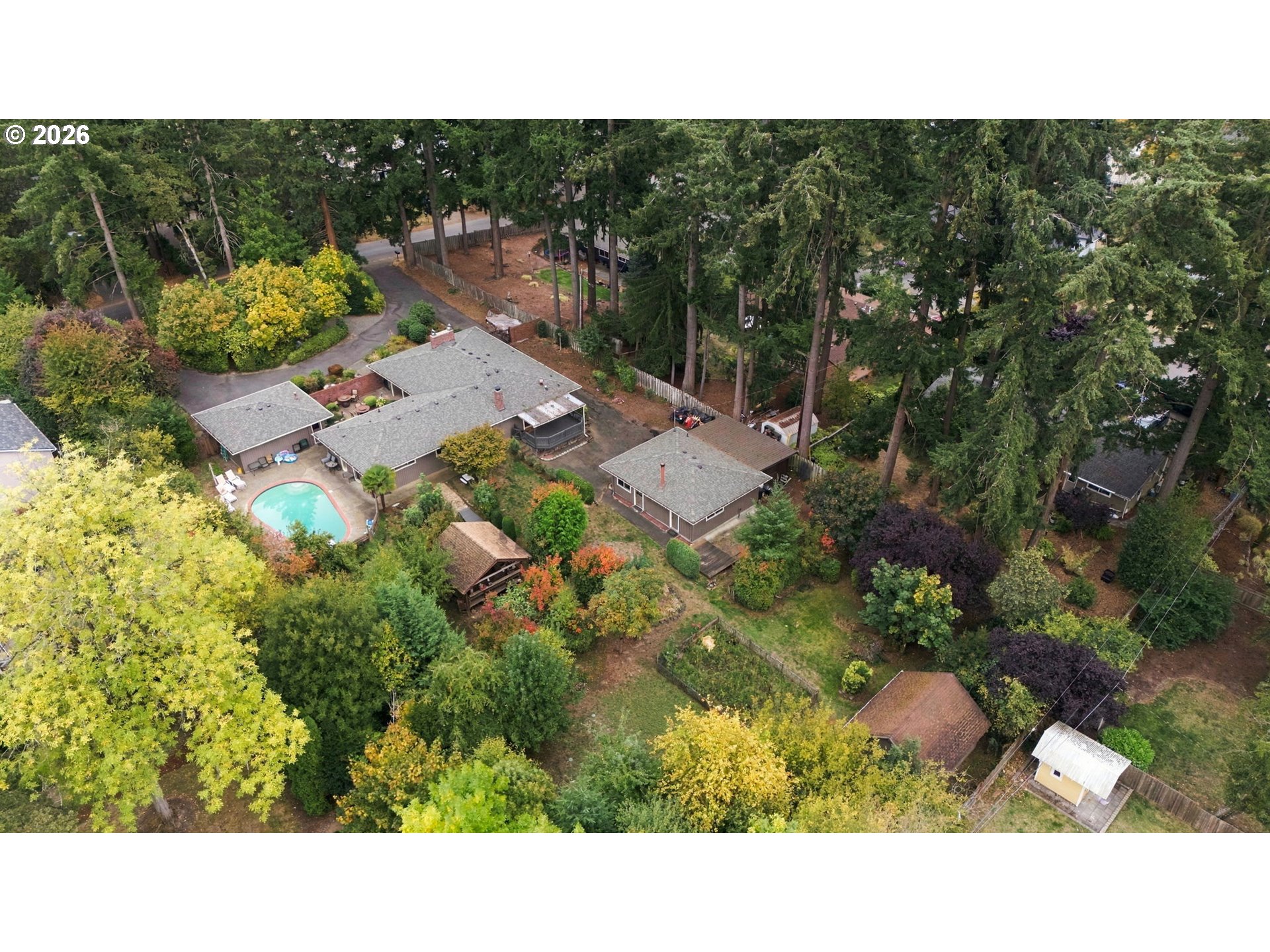 Aerial view of a wooded property with several homes and a swimming pool.