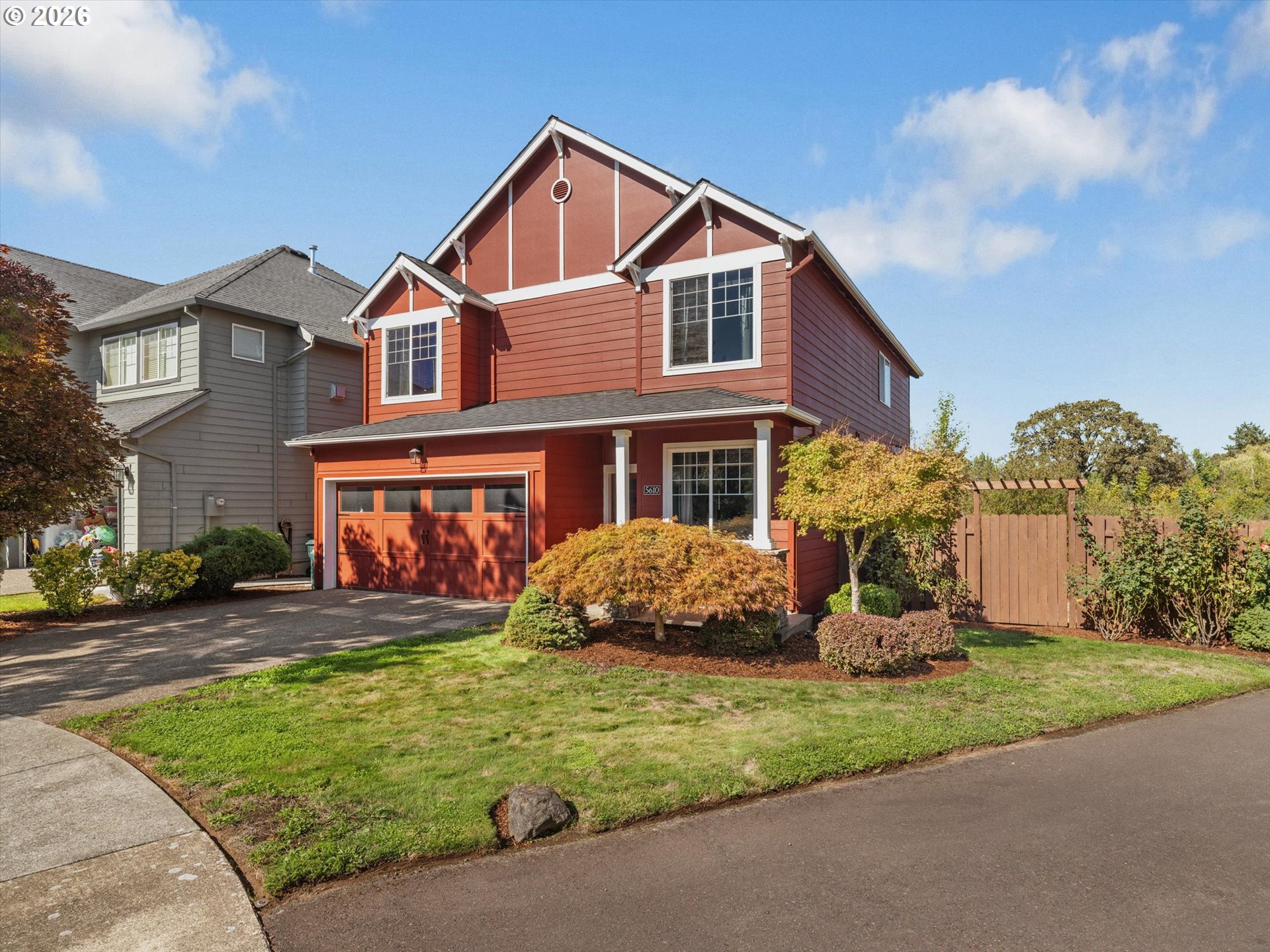 Red two-story house with white trim, garage, and landscaped front yard.
