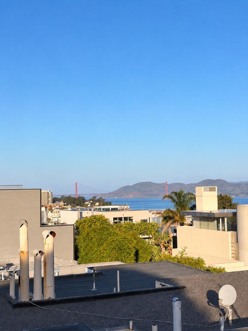 Rooftop view of the Golden Gate Bridge, San Francisco Bay, and distant hills.