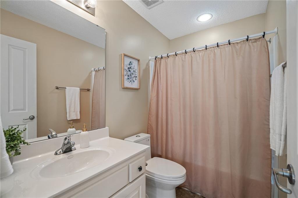 Bathroom with a white vanity, toilet, and pink shower curtain.