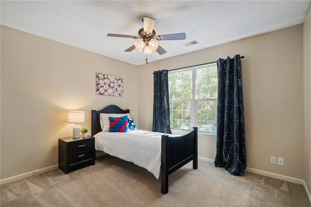 Bedroom with a black bed, colorful accent pillows, and a large curtained window.