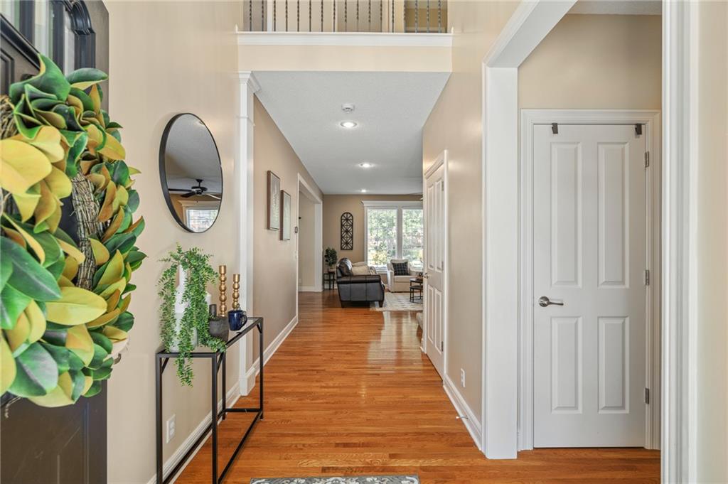 Entry hallway with hardwood floors, a console table, round mirror, and view into the living room.