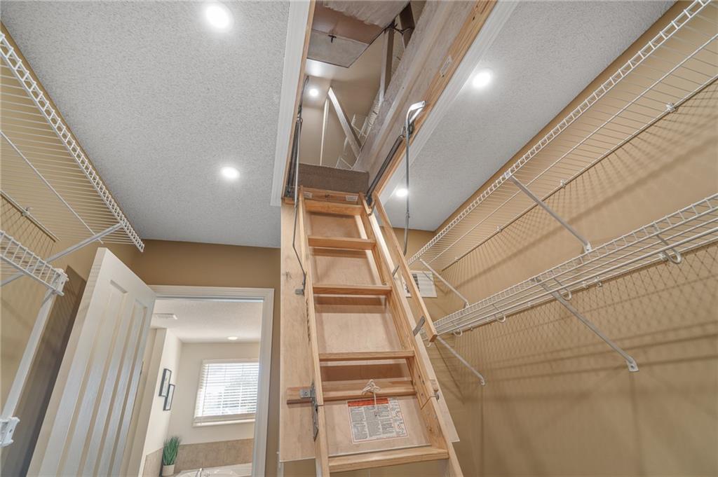 Walk-in closet with wire shelving and an open pull-down attic ladder.