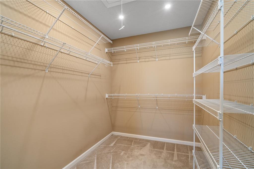 Empty walk-in closet with white wire shelving on three walls and a carpeted floor.