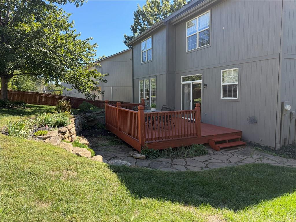 Rear of a gray two-story home with a raised deck and stone patio.
