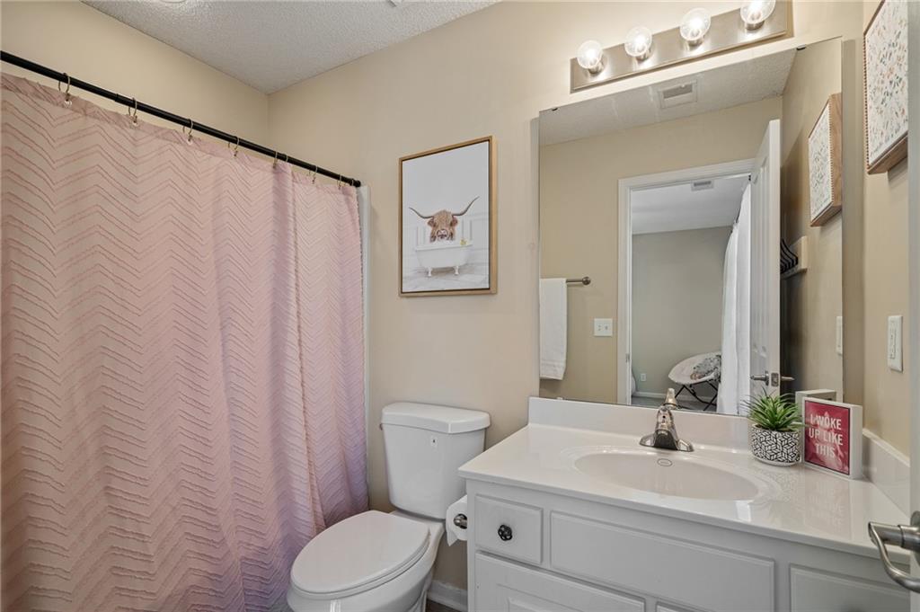 Bathroom with a white vanity, toilet, large mirror, and pink patterned shower curtain.