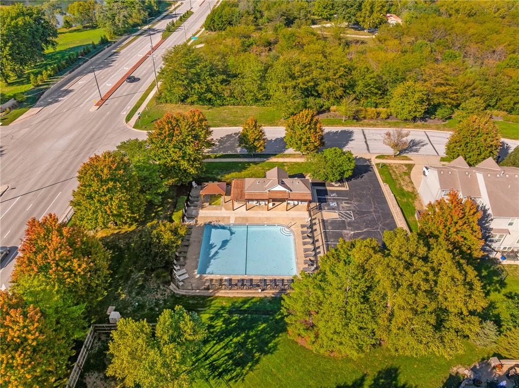 Aerial view of a community pool and covered pavilion surrounded by autumn trees.