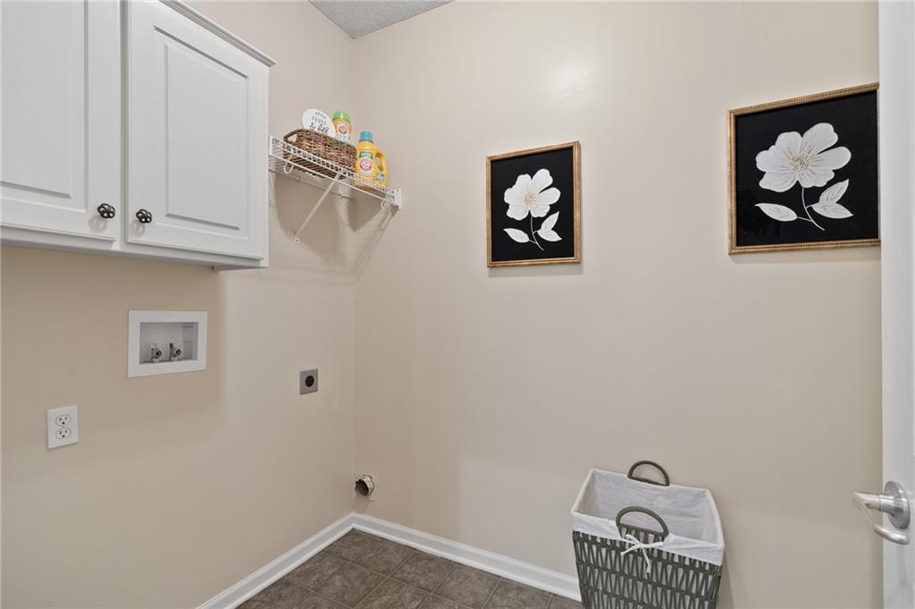 Laundry room with white cabinets, washer and dryer hookups, and framed flower prints.