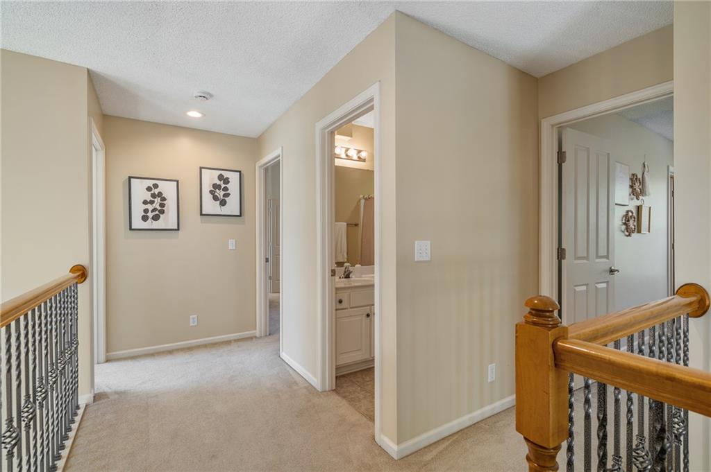 Upstairs hallway with carpet, botanical prints, and wooden stair railings