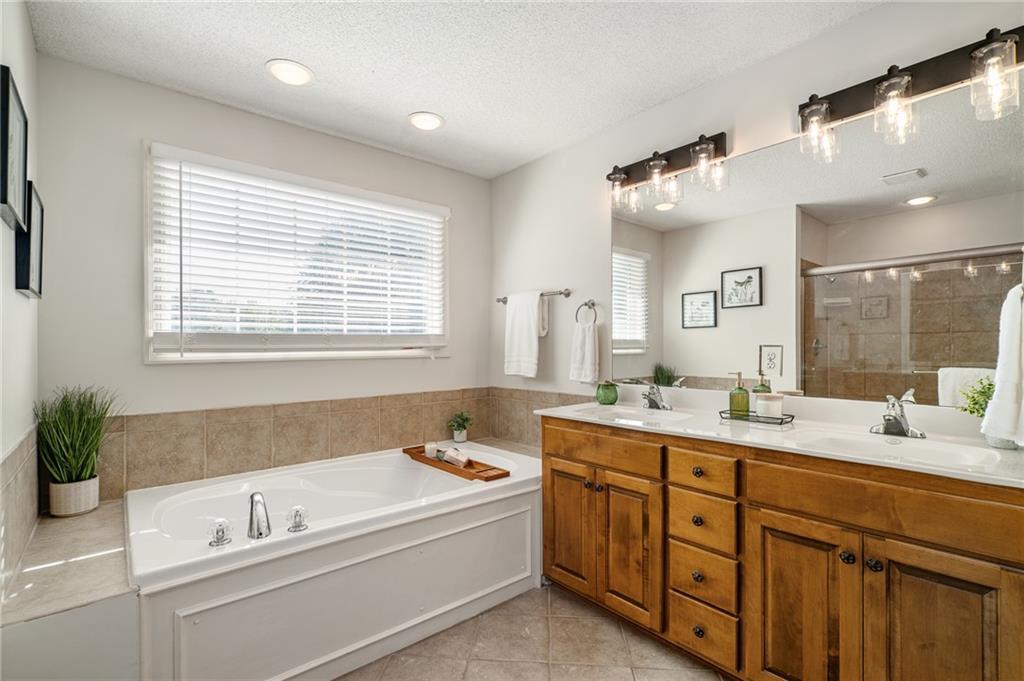 Bathroom with a soaking tub beneath a window and a wood double-sink vanity.