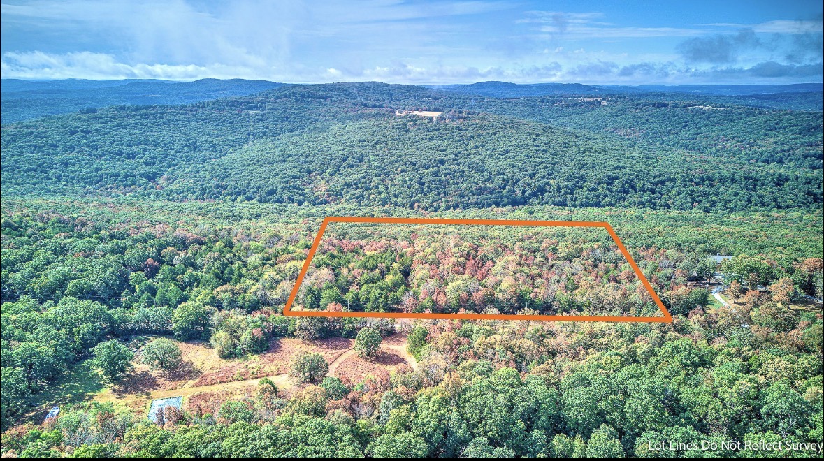Wooded vacant property outlined in orange amid rolling forest and distant ridgelines.