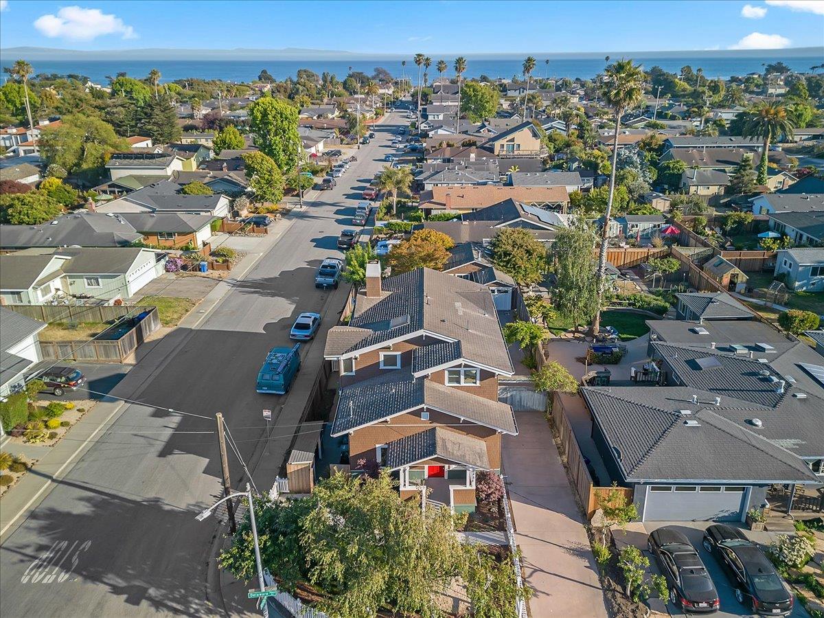 Aerial view of a coastal neighborhood, with a brown home and red front door in the foreground.