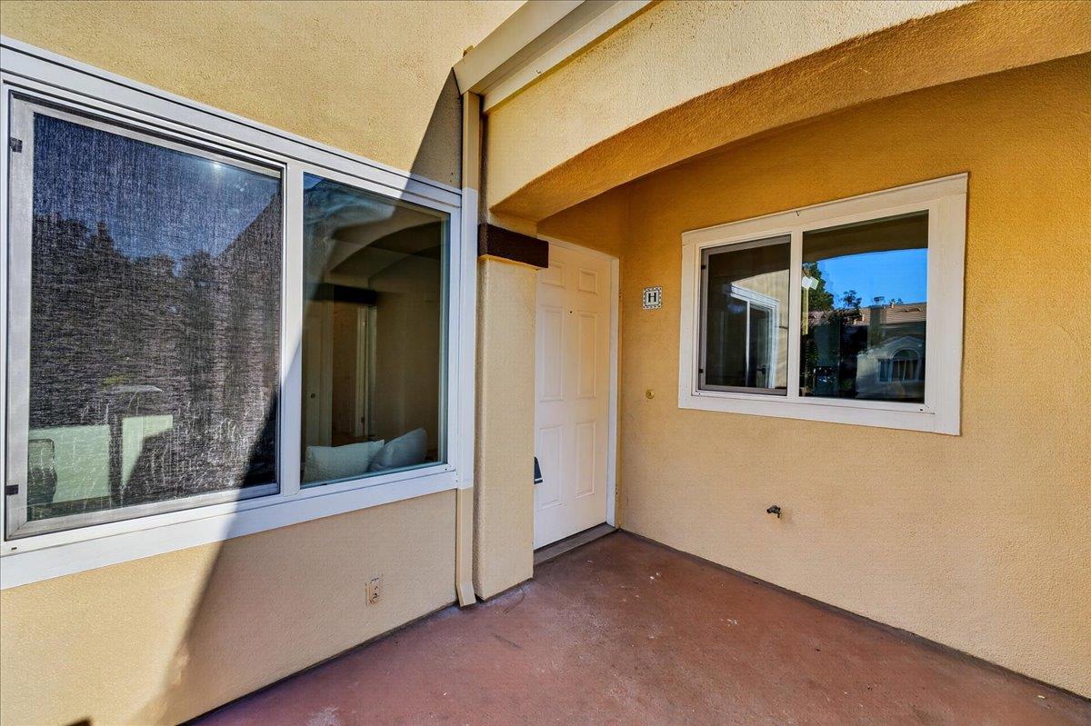 Covered patio entry with a white door, large windows, and yellow stucco walls.