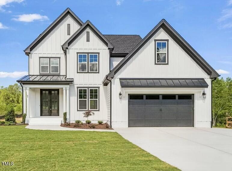 White two-story house with multiple gables, a gray double garage door, and front lawn.