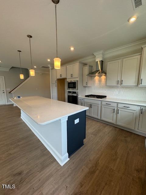 Kitchen with a large white island, gray cabinets, stainless steel appliances, and wood-look floors.