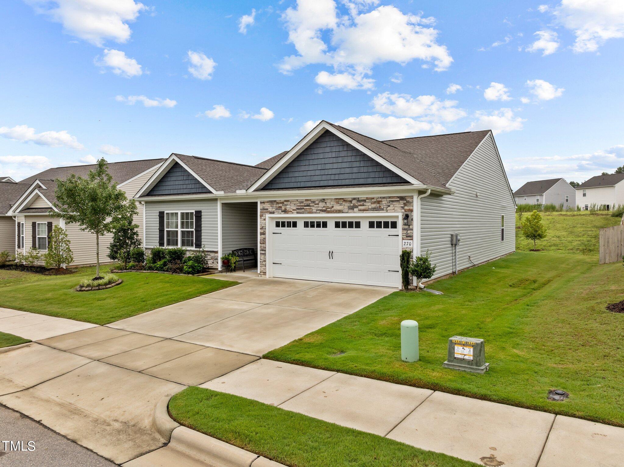 Gray-sided home with stone accents, a two-car garage, and a landscaped front lawn.