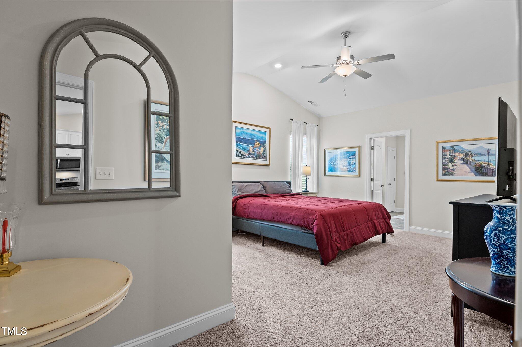 Furnished bedroom with a burgundy-covered bed, high ceiling, and ceiling fan.